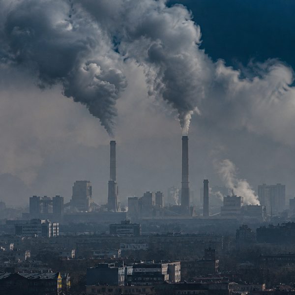 Smokestacks releasing smoke into a smoggy city sky